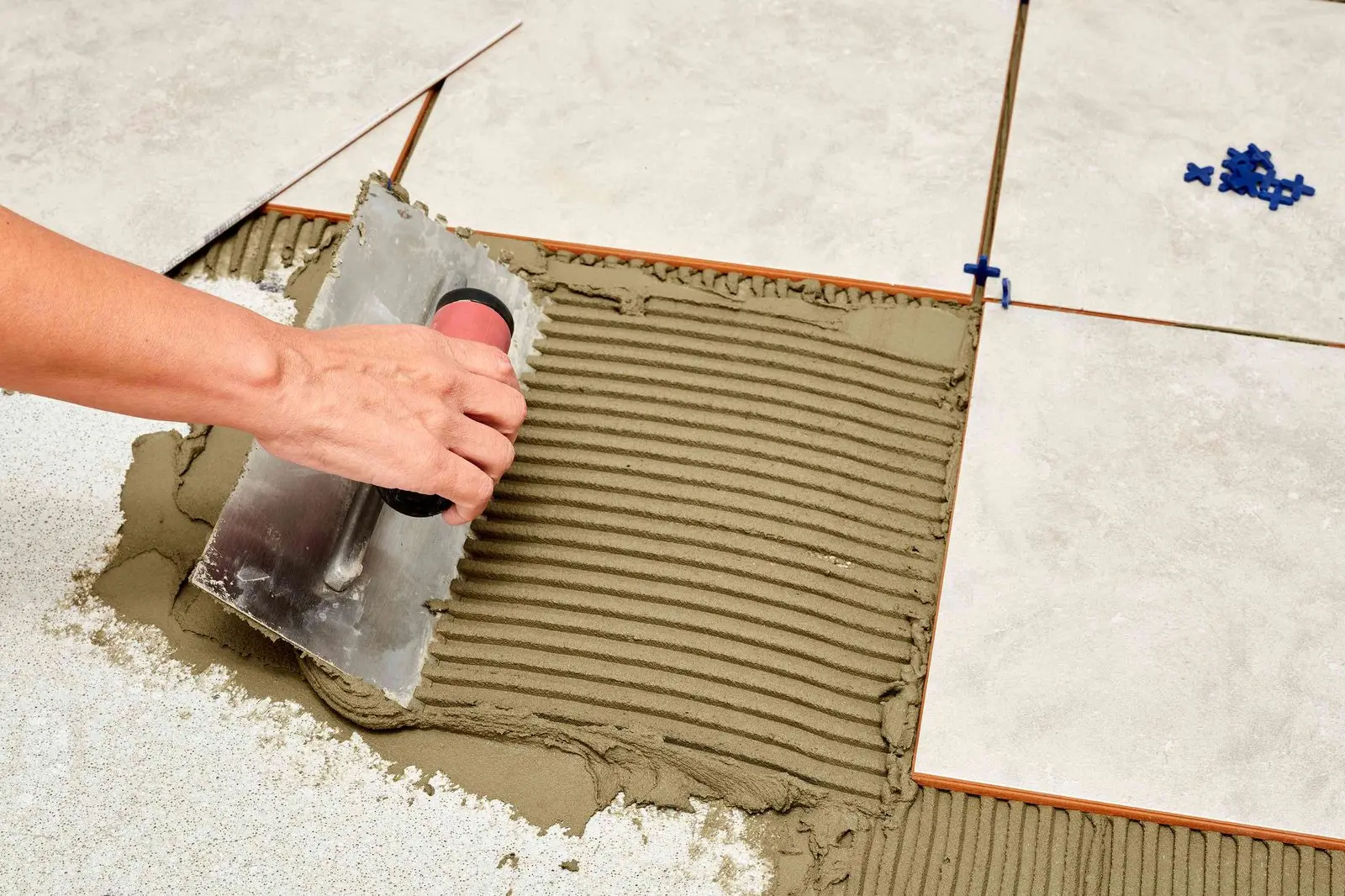Installer spreading thinset with a trowel while setting floor tile