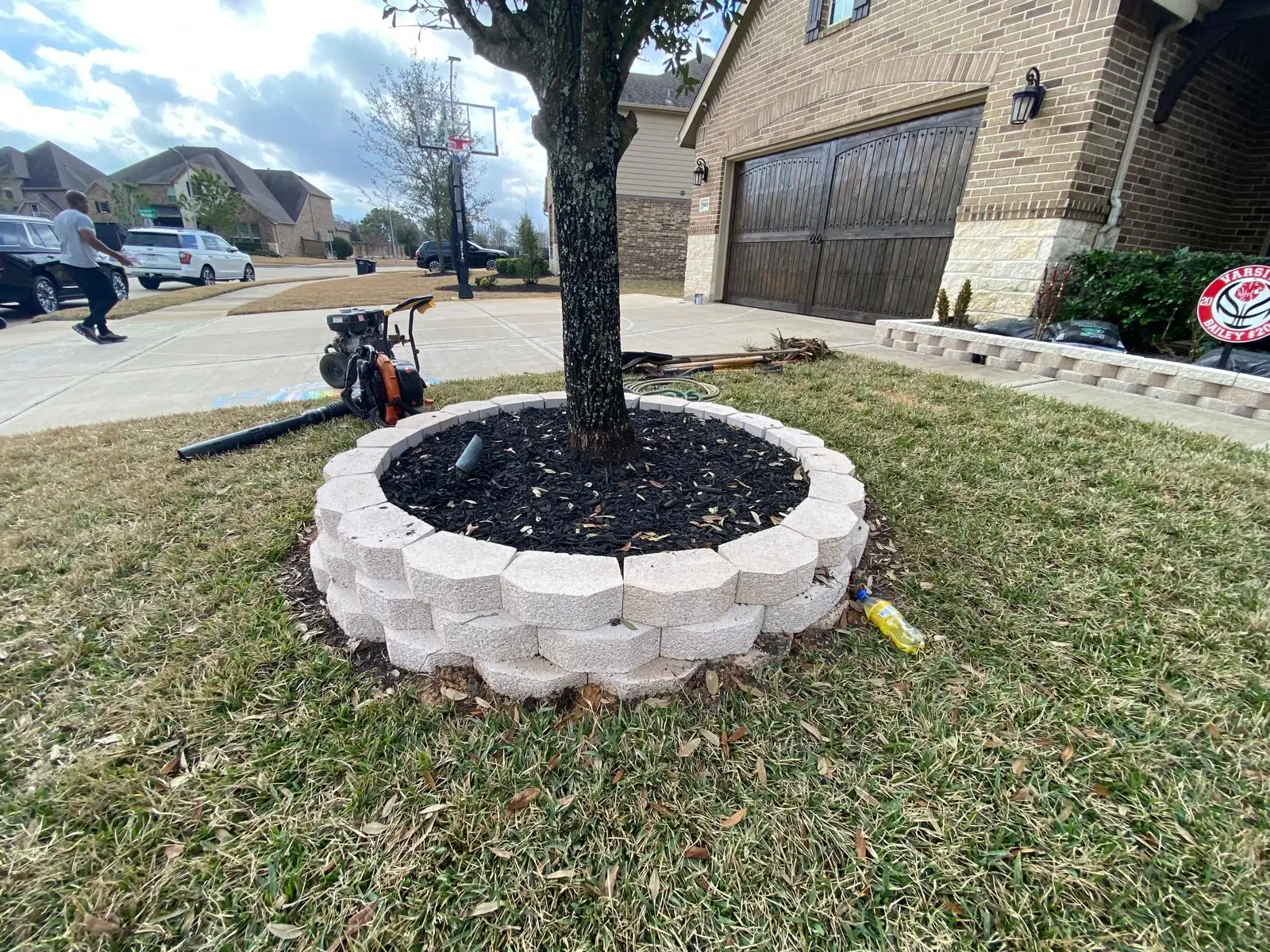 Front yard of a Houston-area home with a tree planter and driveway, with cleaning equipment set up on the lawn